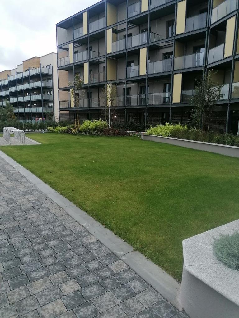 A modern apartment complex with amanicured lawn and a brick sidewalk
